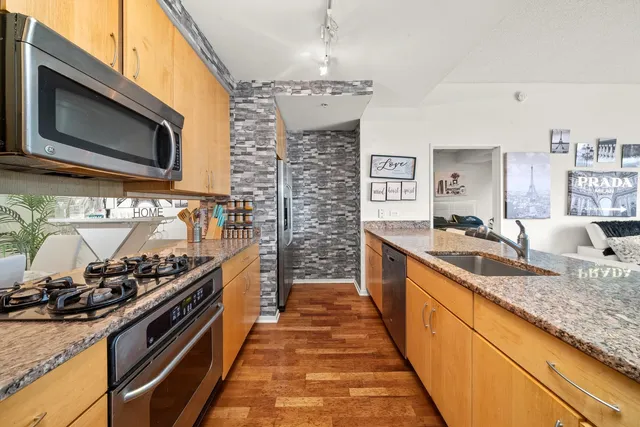 a kitchen with stainless steel appliances granite countertop a stove a sink and a microwave