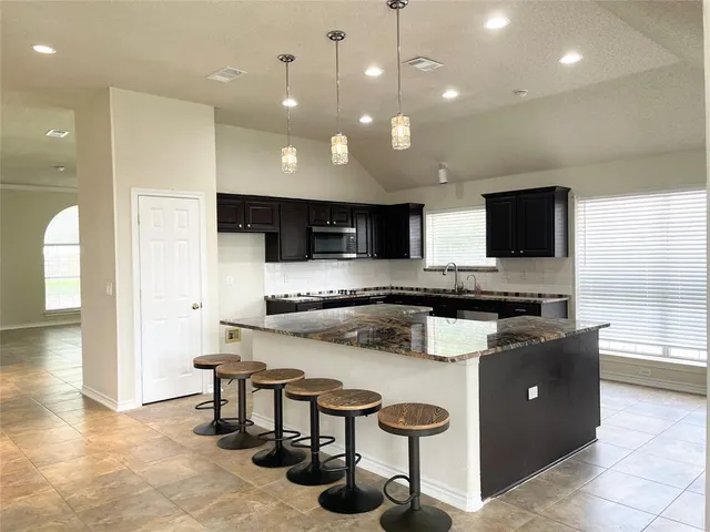 a large kitchen with kitchen island a large counter space a sink and appliances