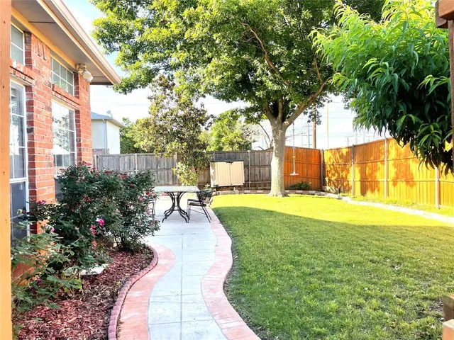 a backyard of a house with plants and large tree