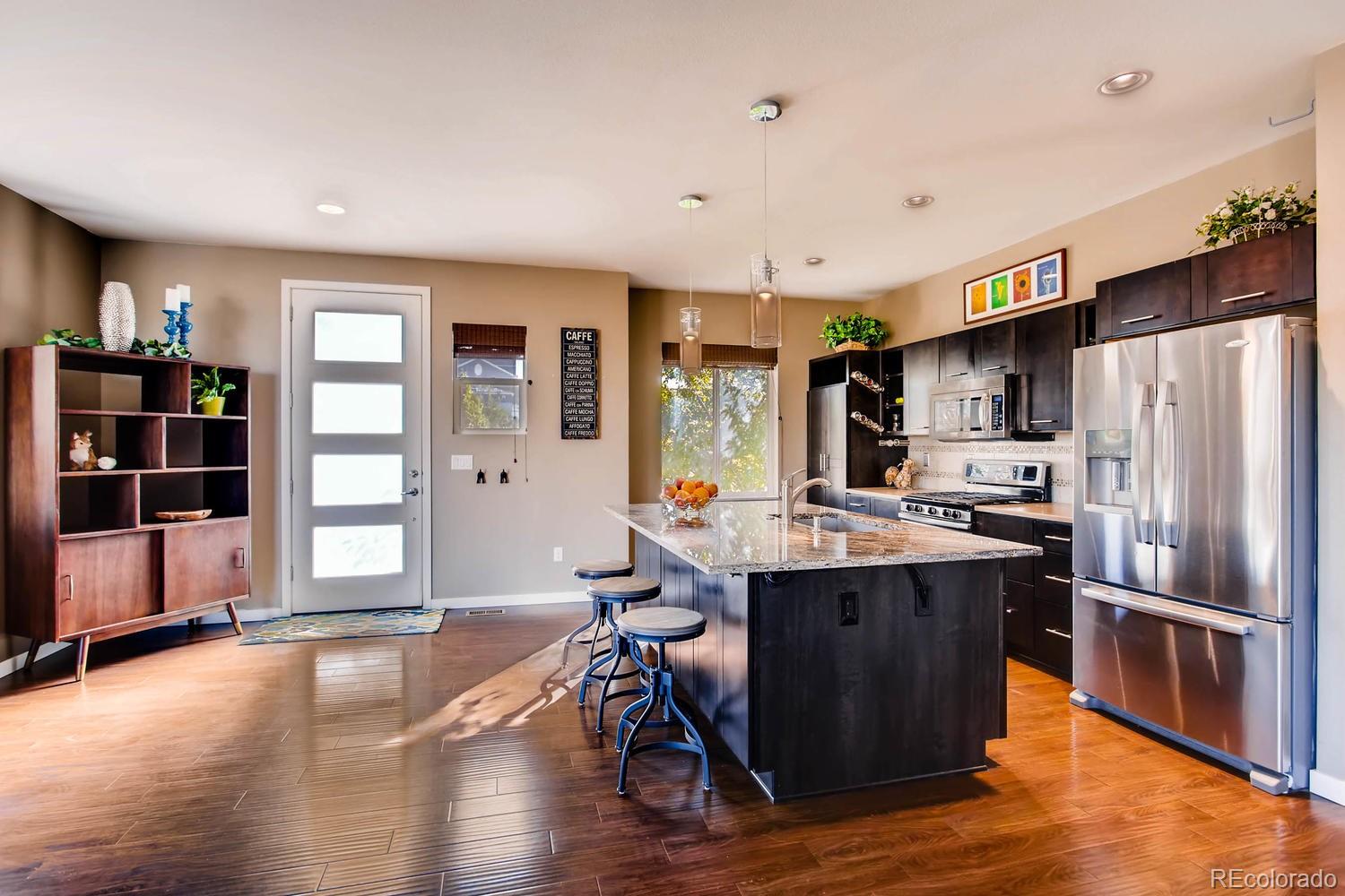 3435 Cranston Circle Highlands Ranch, CO 80126 - Photo 13 of 40 a kitchen with stainless steel appliances a stove a refrigerator a sink dishwasher with wooden cabinets and wooden floor