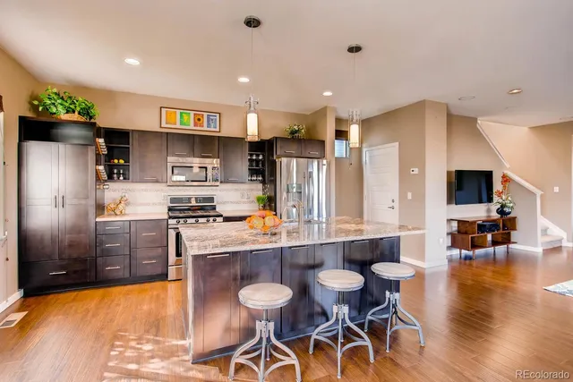 a kitchen with stainless steel appliances a refrigerator a stove top oven a sink dishwasher and white cabinets with wooden floor