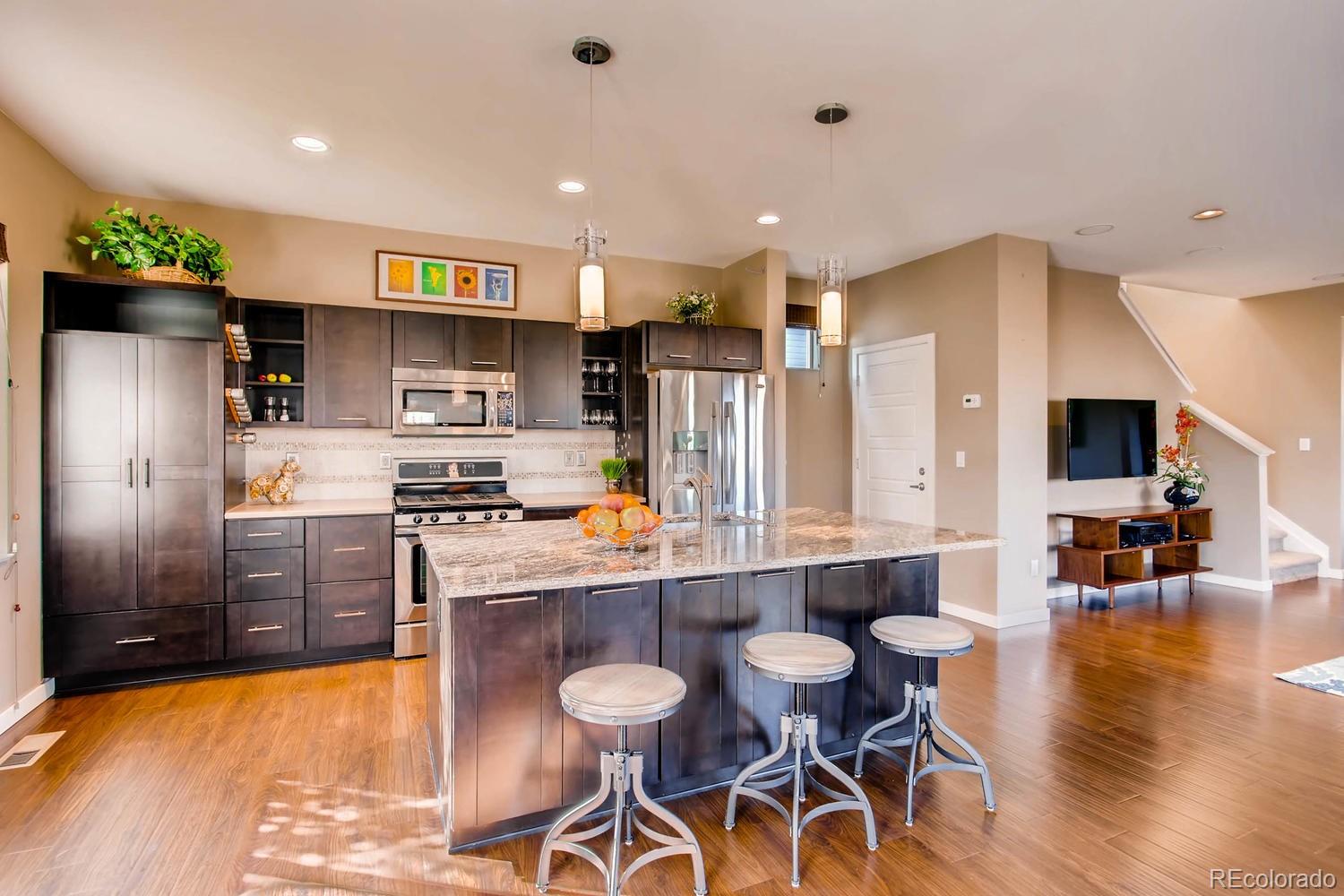 3435 Cranston Circle Highlands Ranch, CO 80126 - Photo 10 of 40 a kitchen with stainless steel appliances a refrigerator a stove top oven a sink dishwasher and white cabinets with wooden floor