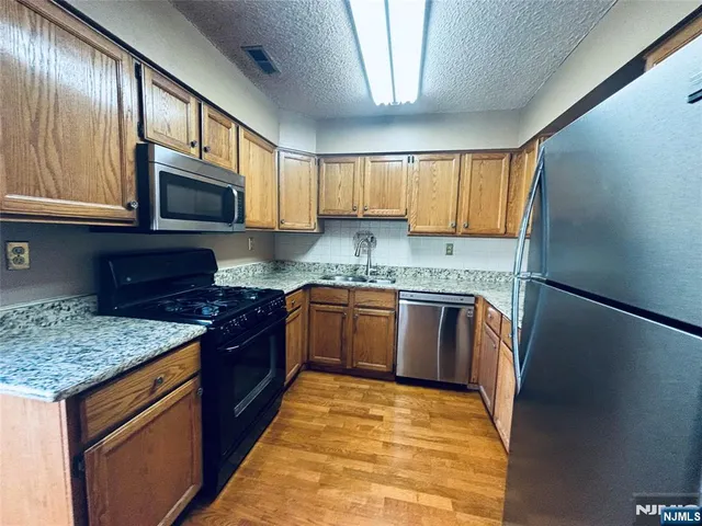 a kitchen with stainless steel appliances granite countertop a stove sink microwave and cabinets
