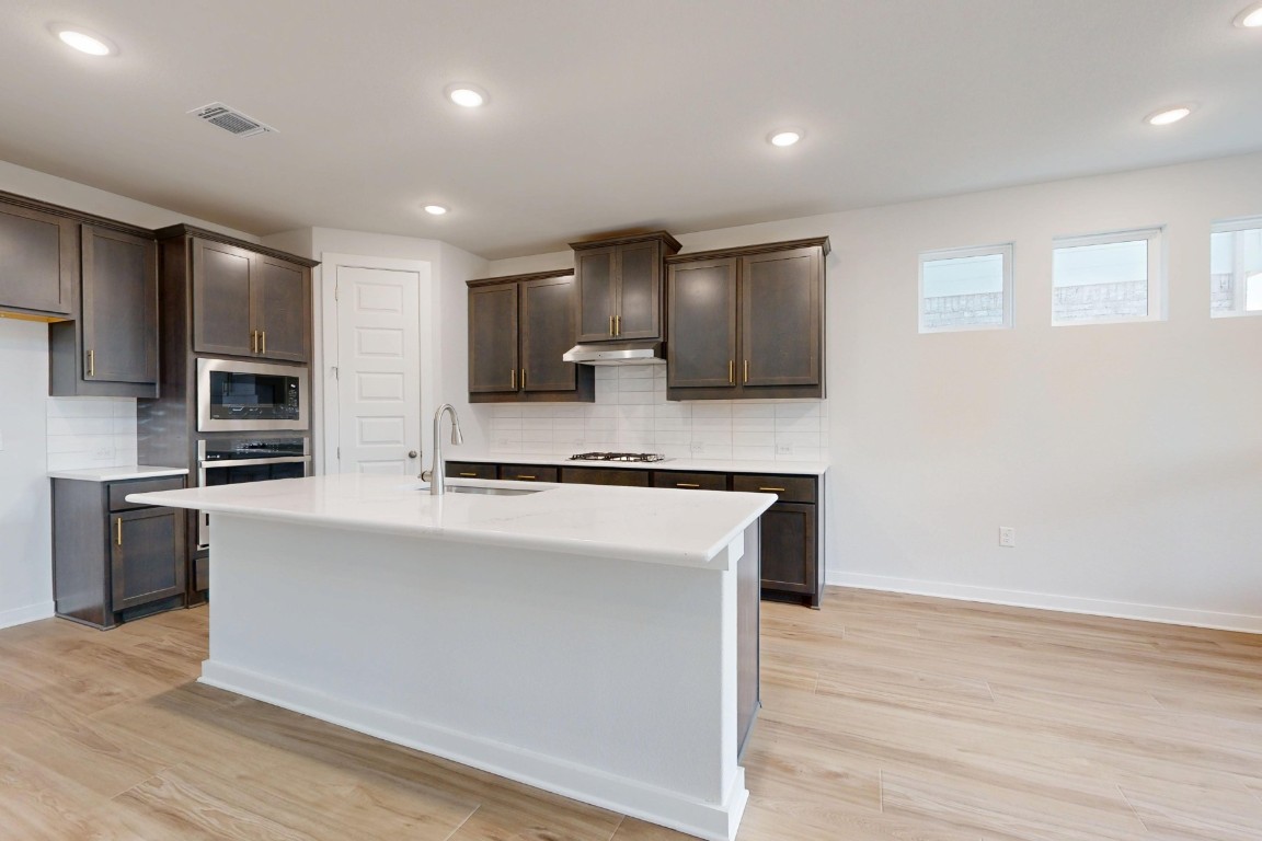 2029 Billings Way Leander, TX 78641 - Photo 3 of 29 a large kitchen with stainless steel appliances granite countertop a stove a sink and a microwave