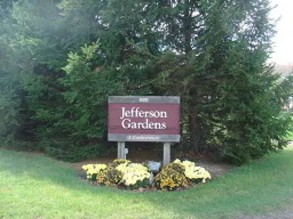 a sign that is sitting in the grass near a tree