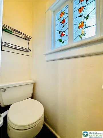 a white toilet sitting next to a small window