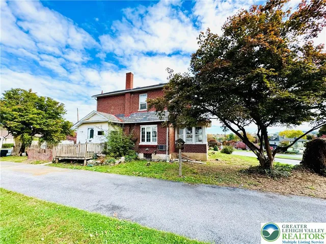 a front view of a house with a garden and tree