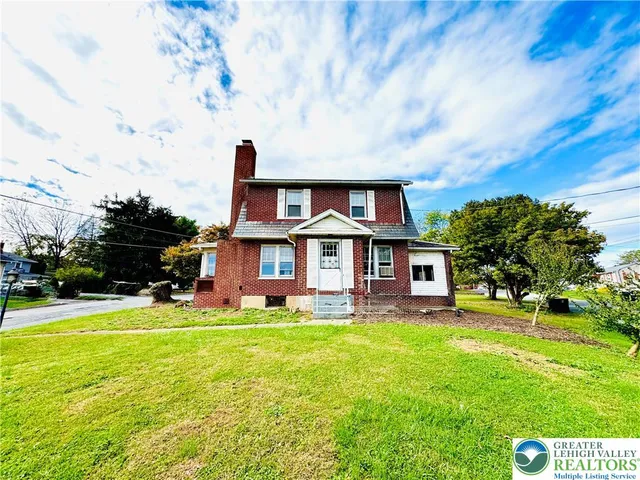 a view of a house with a big yard and large trees
