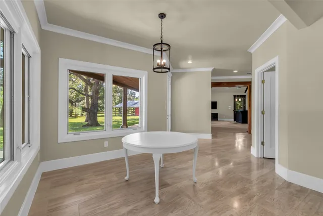 a dining room with wooden floor a chandelier a wooden table and chairs
