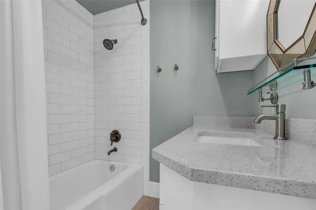 a bathroom with a granite countertop sink a mirror and bathtub