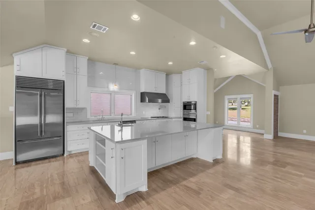 a large kitchen with a large counter top stainless steel appliances and cabinets