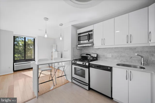 a kitchen with stainless steel appliances granite countertop white cabinets and window