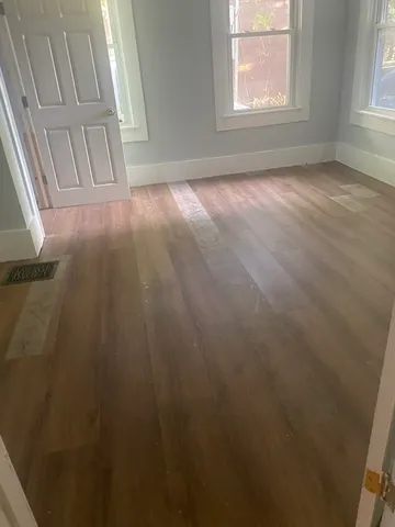 an empty room with wooden floor and windows