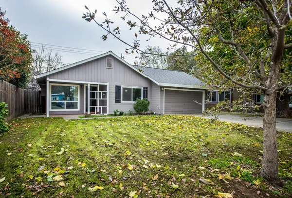 a view of a house with a large tree and a yard