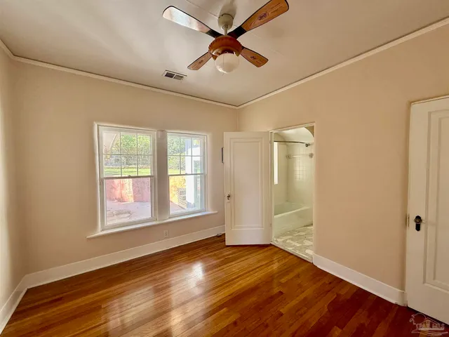 a view of an empty room with window and wooden floor