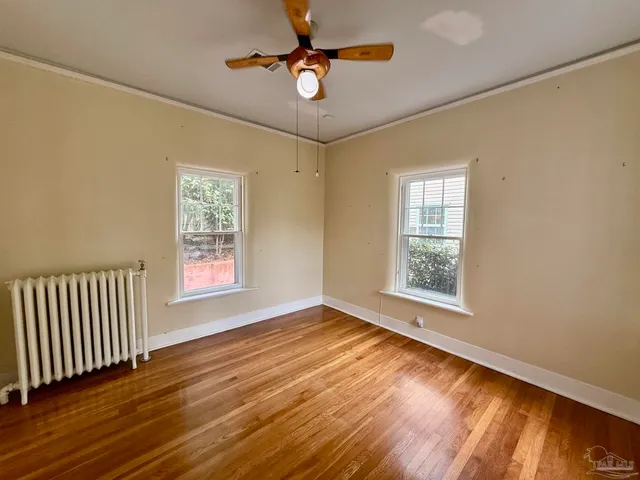 a view of an empty room with window and wooden floor