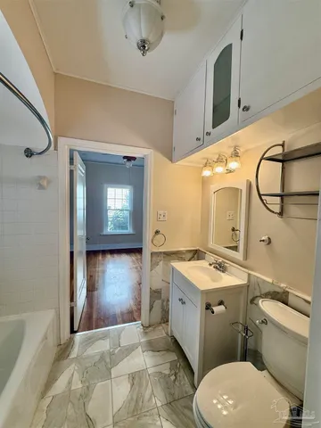 a bathroom with a granite countertop toilet sink and mirror