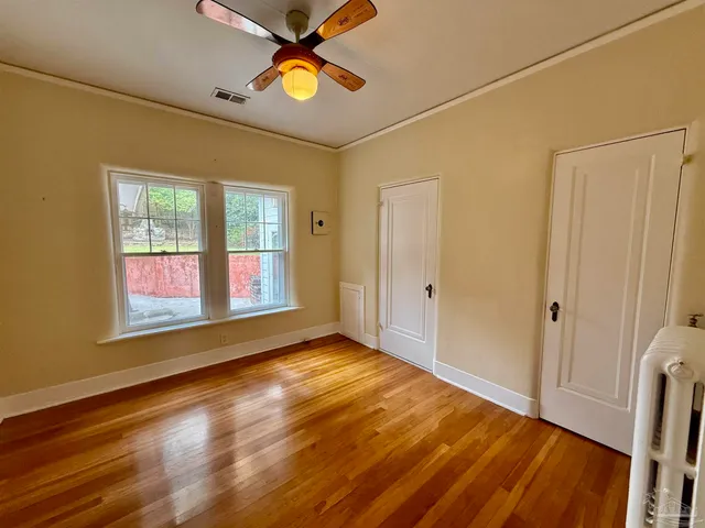a view of an empty room with window and wooden floor