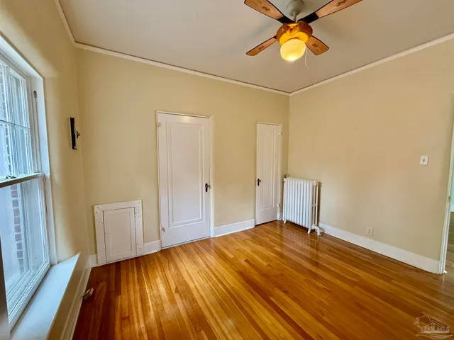 a view of an empty room with window and wooden floor
