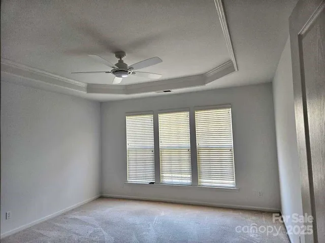 an empty room with a ceiling fan and windows