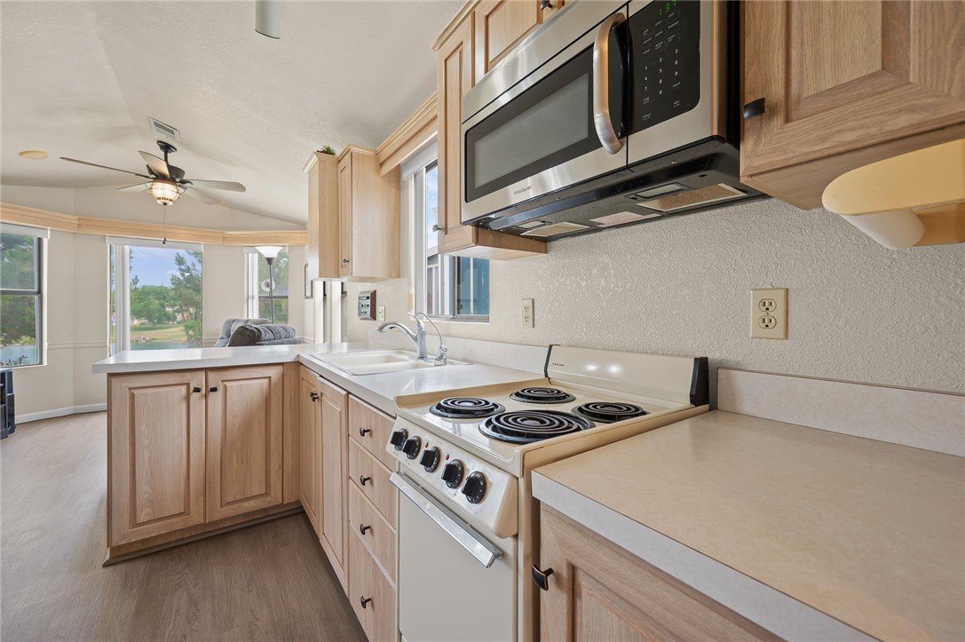 2000 Ramar Road, Unit 612 Bullhead City, AZ 86442 - Photo 19 of 77 Kitchen with electric stove, light brown cabinetry, stainless steel microwave, a peninsula, and light wood finished floors