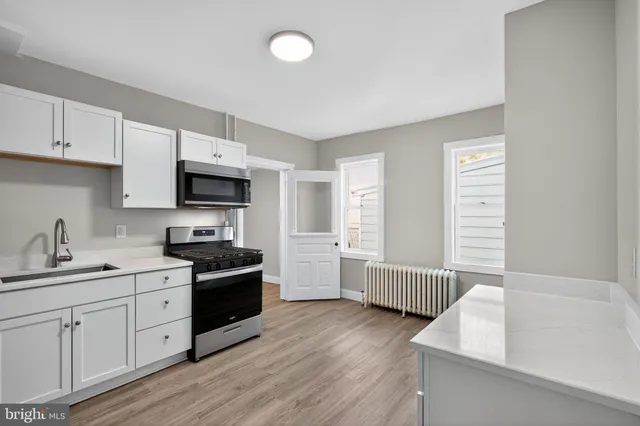 a kitchen with stainless steel appliances granite countertop a sink dishwasher a stove and a refrigerator with wooden floor