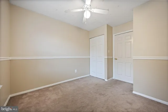 an empty room with closet and a ceiling fan