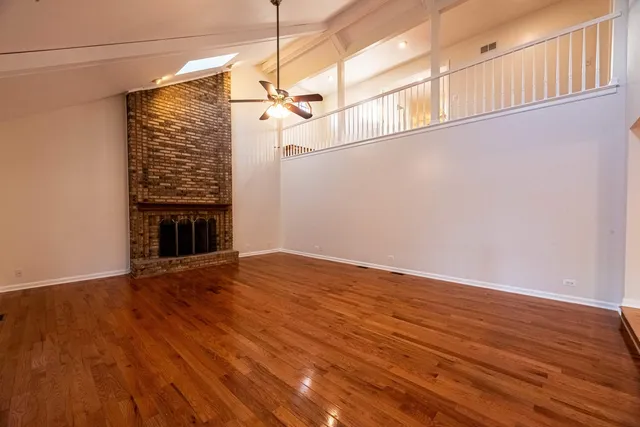 a view of empty room with wooden floor and fireplace