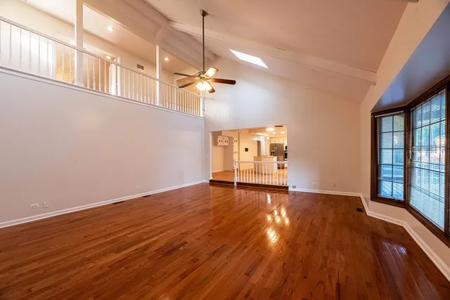 a view of empty room with wooden floor and fan