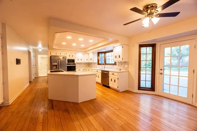 a living room with stainless steel appliances kitchen island hardwood floor and a large window