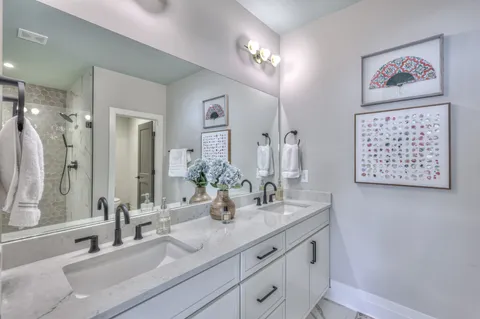 a bathroom with double vanity sinks a shower and a mirror