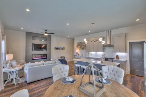 a living room with furniture kitchen view and a wooden floor
