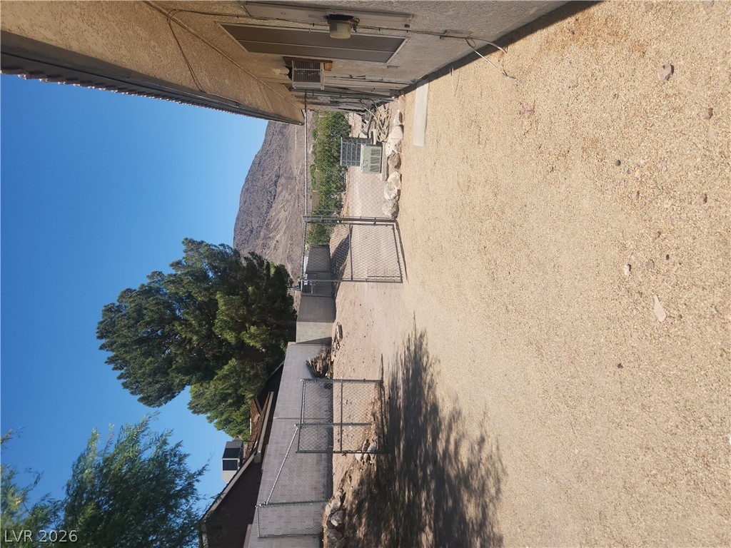 564 Ridgeway Road Henderson, NV 89015 - Photo 21 of 22 A spacious gravel yard with chain-link fencing offers ample outdoor potential against a desert mountain backdrop.