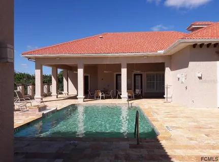 a view of swimming pool with lawn chairs and iron fence
