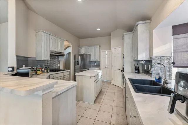 a kitchen with stainless steel appliances a sink a stove top oven a counter space and cabinets