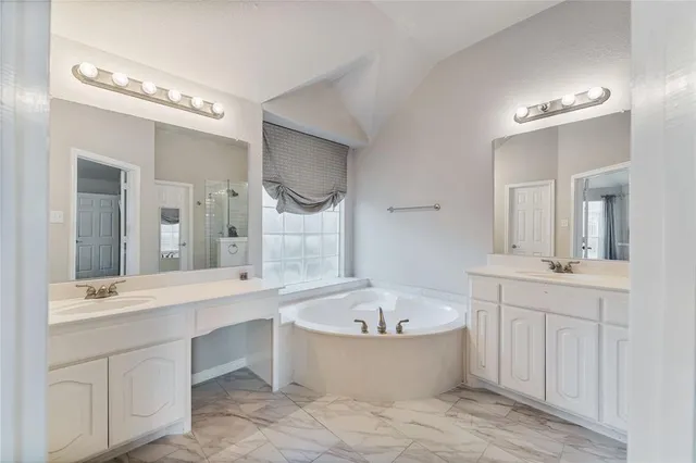 a bathroom with a tub a double vanity sink and a mirror