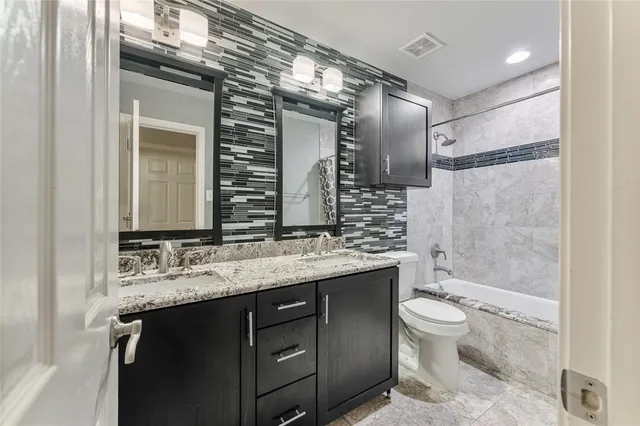 a bathroom with a granite countertop sink toilet a mirror a vanity and bathtub
