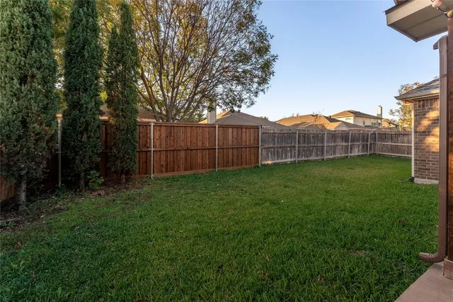 a view of a backyard with a large tree and wooden fence
