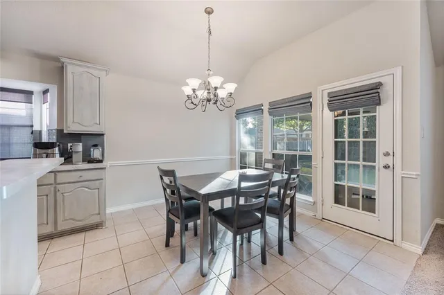 a dining room filled chandelier and kitchen view