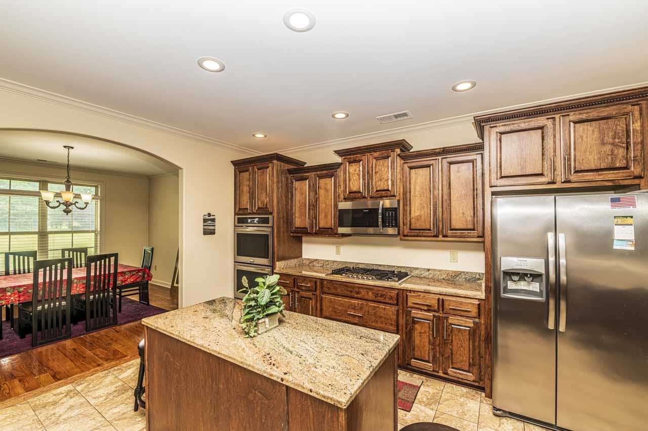 185 Belmont Road Mason, TN 38049 - Photo 26 of 38 Kitchen featuring wood cabinetry with crown molding, granite countertops, stainless steel appliances, and recessed lighting