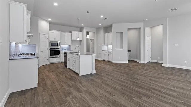a kitchen that has a lot of cabinets in it and wooden floor