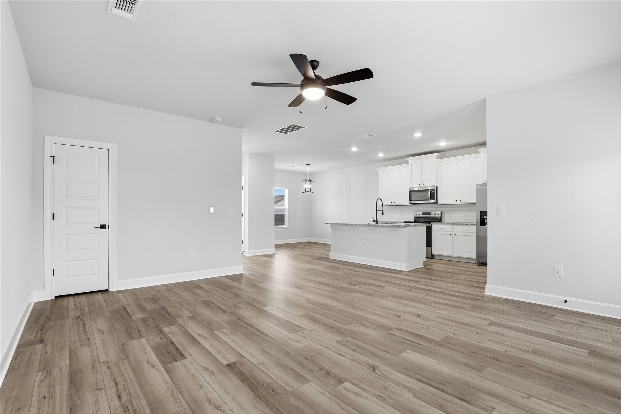 9320 Gladsome Path Manor, TX 78653 - Photo 9 of 34 a view of an empty room with wooden floor and a ceiling fan