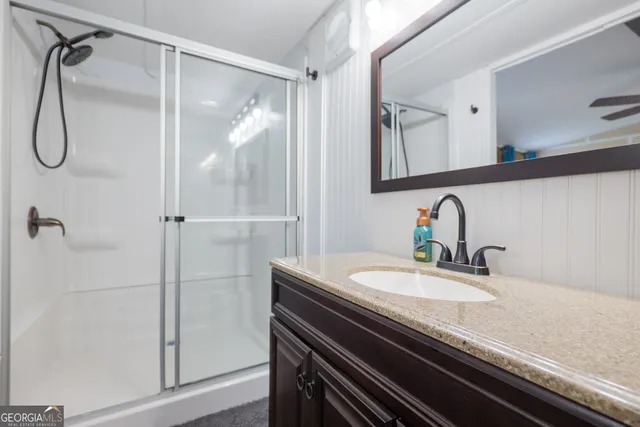 a bathroom with a granite countertop sink a mirror and shower