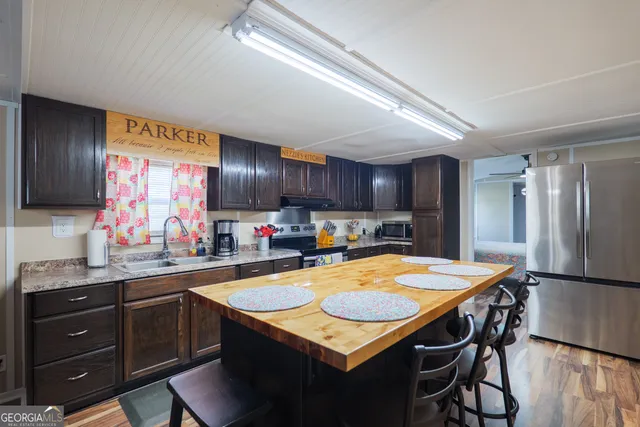 a kitchen with stainless steel appliances kitchen island granite countertop a table chairs sink and refrigerator