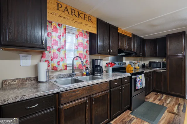 a kitchen with granite countertop a sink a stove and a wooden cabinets