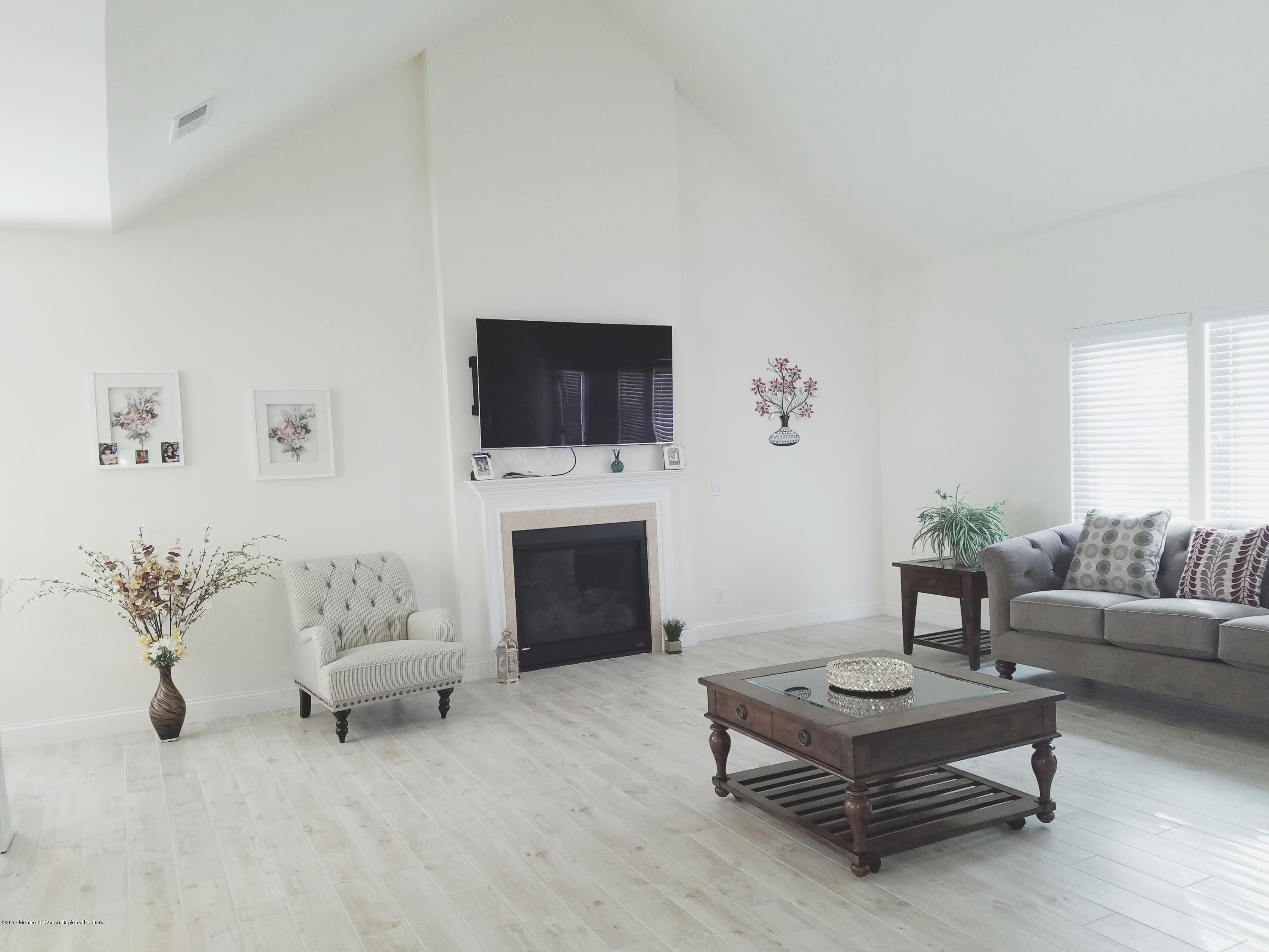 12 Cindy Court Howell, NJ 07731 - Photo 25 of 64 a living room with furniture a fireplace and a flat screen tv
