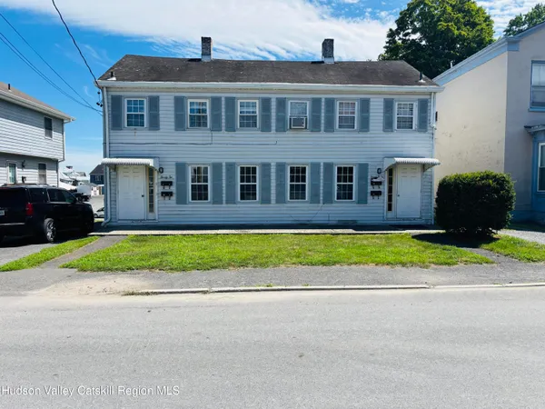 a front view of a house with a yard and potted plants