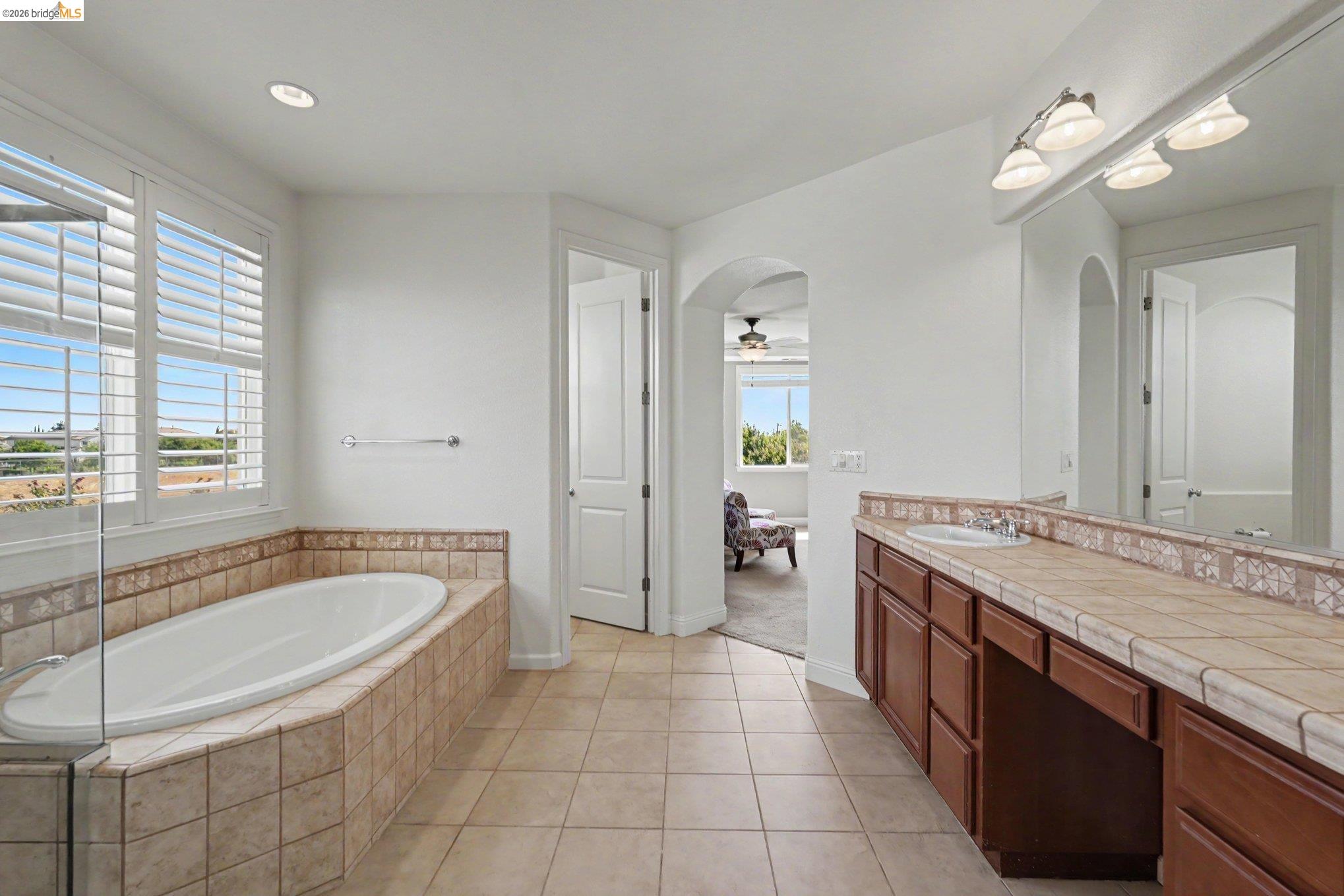 106 Little Ranch Circle Oakley, CA 94561 - Photo 24 of 34 Tile flooring bathroom featuring a built-in soaking tub with tiled surround, a long vanity with dual sinks, and a large mirror