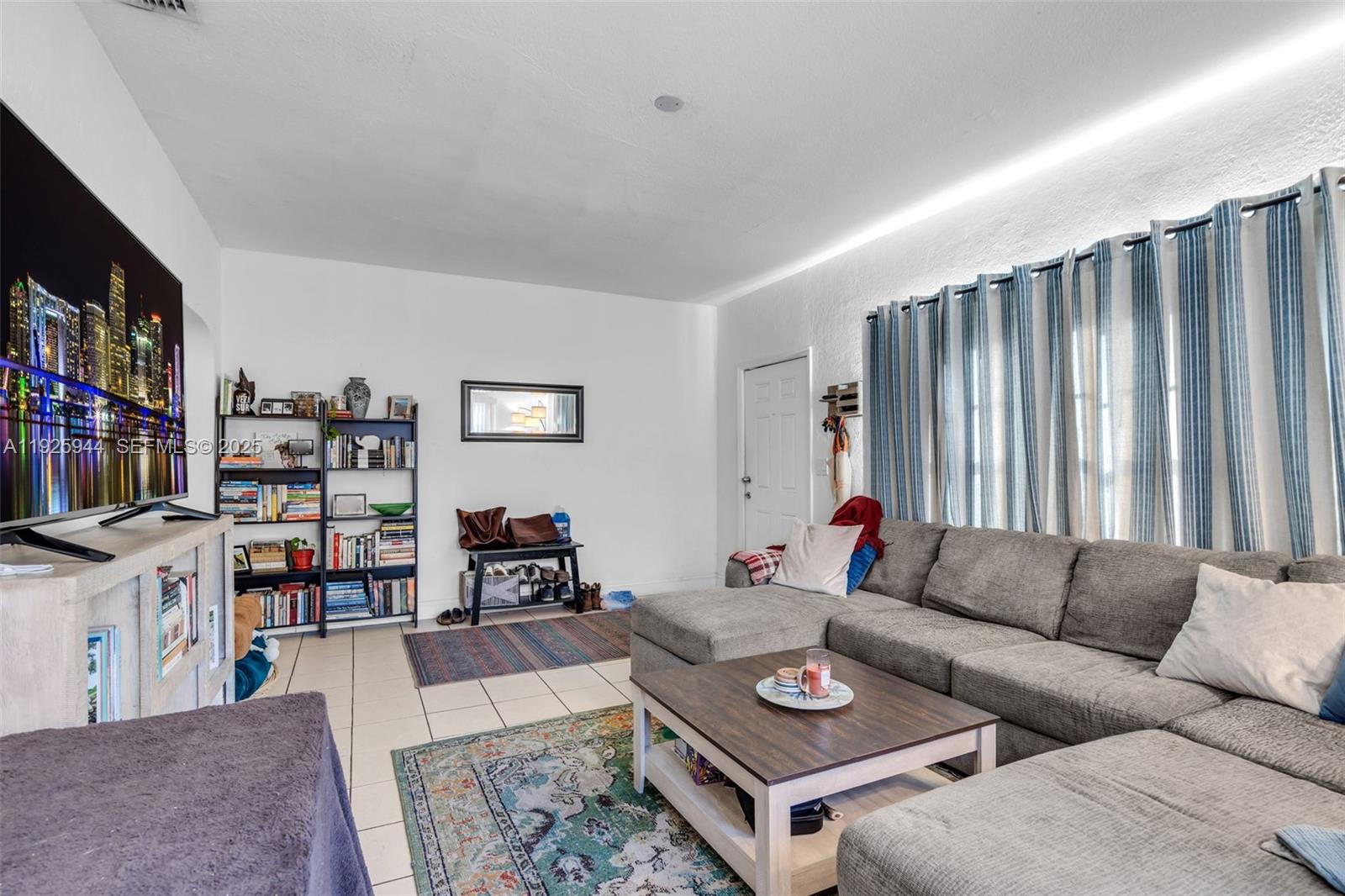 2271 Southwest 11th Street Miami, FL 33135 - Photo 5 of 17 a living room with furniture a bookshelf and a flat screen tv