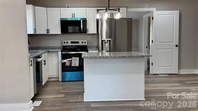 a kitchen with stainless steel appliances granite countertop a refrigerator and a stove top oven